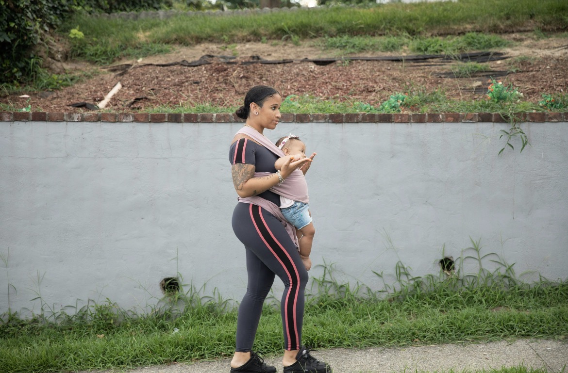 A mum walking outdoors with her baby carried in a wrap